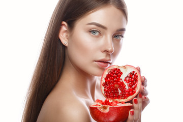 Beautiful young girl with a light natural make-up and perfect skin with pomegranate in her hand....