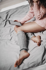 Fototapeta premium Girl sitting on bed in the morning and using tablet for reading news