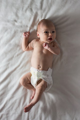 Little Baby in a White Nappy Lies on a white blanket. White background. Flat lay, top view