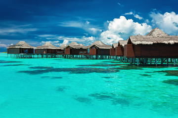 Over water bungalows with steps into lagoon with coral