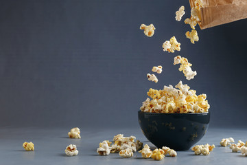 Popcorn flying into the bowl over grey background - obrazy, fototapety, plakaty