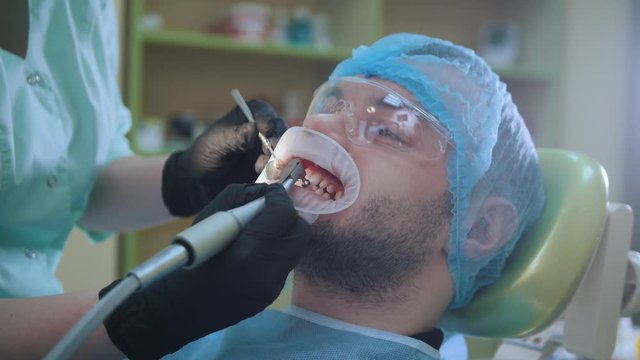 Doctor and patient with lip dilator in the dental office, polishing with special brush