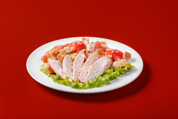 Caesar salad with chicken, tomatoes, breadcrumbs, cheese top, decorated with lettuce leaves on a monophonic background. Side view