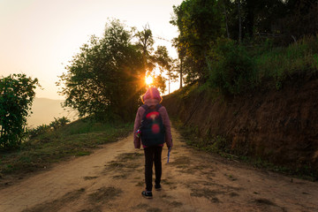 Countryside student young girl walking on mountain trail at morning time.