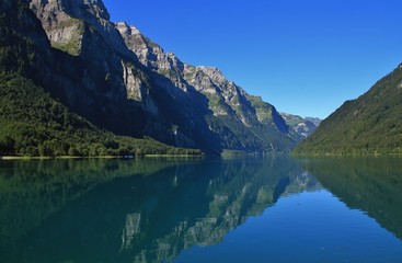 Glarnisch, mountain range in Glarus canton reflecting in lake Klontalersee. Quiet summer day in Switzerland.