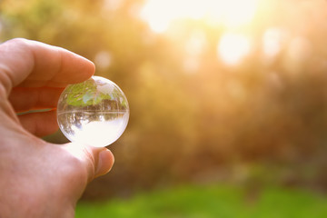 male hand holding small crystal globe. travel and global issues concept.