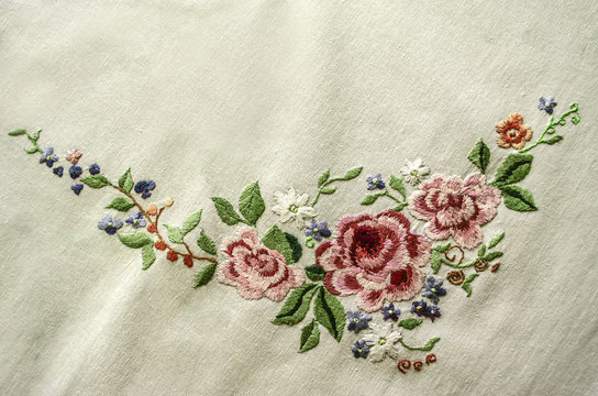 Embroidery satin stitch pink roses with other flowers and leaves on cotton cloth
