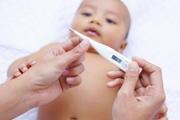 Mother Measures The Temperature Of Her Baby Using Digital Thermometer 