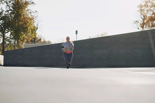 Curvaceous young female runner running in urban setting