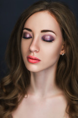 Beautiful model wearing golden dress is posing in a dark studio 