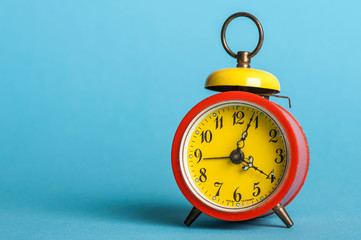 old, colorful alarm clock, in front of blue background