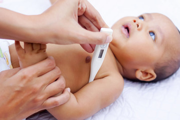 Mother Measures The Temperature Of Her Baby Using Digital Thermometer 