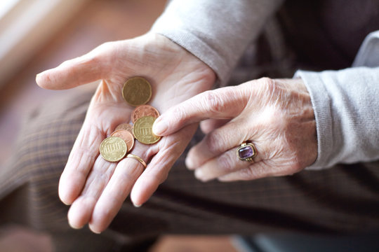 Senior woman counting coins in hand, close-up