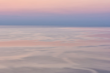 Fototapeta na wymiar Nice pink sunset seascape in pastel shades, peace and calm outdoor travel background with copy space, motion blur image