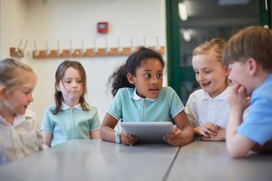 Schoolgirls and boy using digital tablet in classroom lesson at primary school