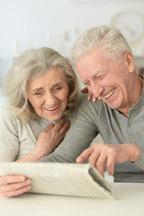 senior couple with newspaper  at home 