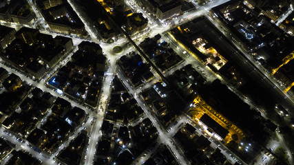 Panoramic night aerial view of the Tuscolana district, in the city of Rome in Italy. The streets and buildings are illuminated by street lamps and car headlights.