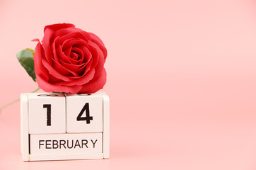 Red rose with calendar February 14th Valentine's Day on pink background Copy space