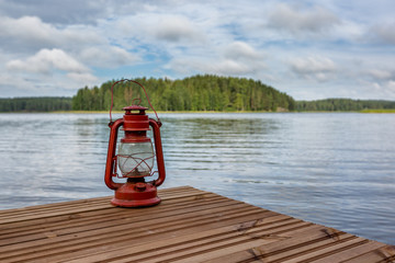 Old red kerosene lamp and lake, Finland