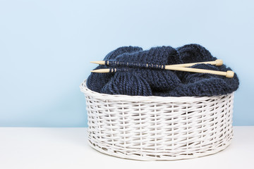 Obraz premium Basket with woolen yarn and knitting needles, balls of thread. Copy space for text.