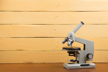 Education concept - microscope on the yellow wooden background