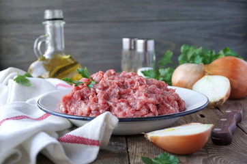 Fresh raw ground meat in a plate on a wooden table