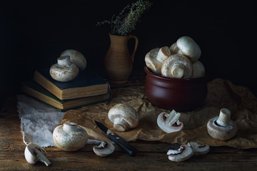 ...Mushrooms champignons on an old rustic wooden table on a dark background. Low key. Focus concept. .Vintage style....