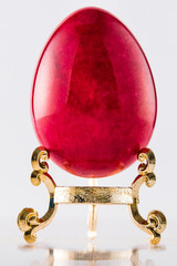 One marble textured stone epensive red and fashionable easter egg on a gold stand for easter holidays. - 192002344