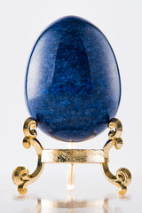 One marble textured stone epensive dark blue and fashionable easter egg on a gold stand for easter holidays. - 192002368