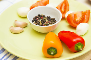 Set of raw ingredients for Italian salad on a plate and tablecloth background. Garlic, salad, tomatos, red and yellow papper. Set of healthy food products. Closeup