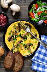 Frittata with mushrooms and cheese for breakfast with salad on a wooden background.