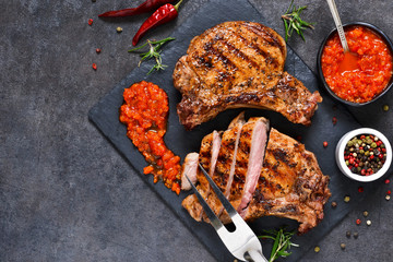 Grilled beef steak with spices and tomato sauce on a stone board.