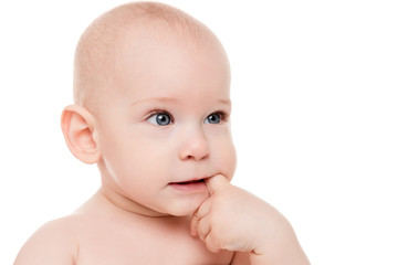 Adorable baby boy with blue eyes sucking on his finger, looking away from camera. Cute teething toddler boy close up portrait isolated on white background.