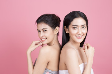 Portrait of Two Beautiful Asian Woman. Beautiful Woman looking to camera.  People with Youth and Skin Care Concept. isolated on pink background.