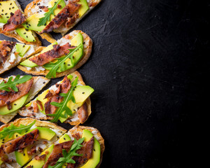 Avocado sandwich on homemade ciabatta bread made with fresh sliced avocados and fried crispy bacon from above. Top view image. Copyspace for your text.