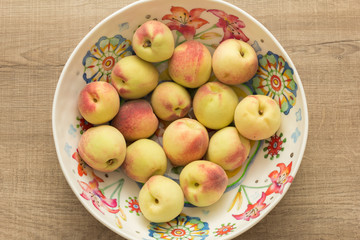 Peaches and colorful bowl. Fruits on wooden table. Overhead, flat lay of vegetables.