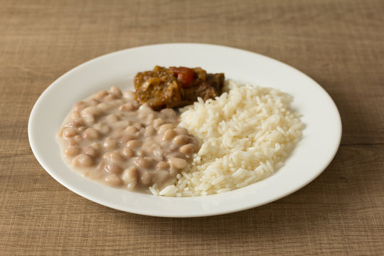 White Rice, Pinto Beans And Meat With Sauce. White Dish On Wooden Table. Detail Of Food Dish, Closeup, Selective Focus.