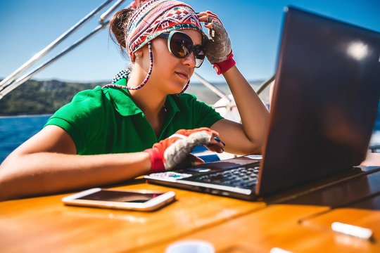 Young woman looking at laptop aboard yacht near coast, Croatia