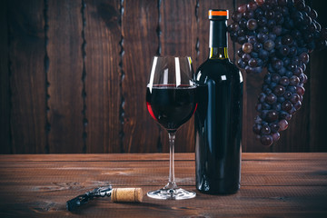 Bottle and glass of red wine, grape and cork on wooden background. © Ievgenii Meyer