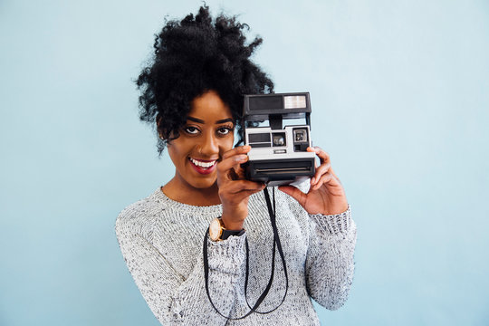 Woman with instant camera looking at camera smiling