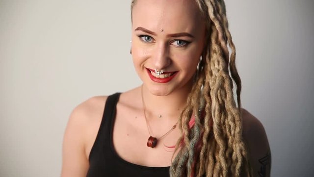modern youth. portrait of a cheerful beautiful girl of unusual appearance - dreads, piercings and tattoos.