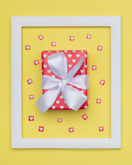 Happy Mother's Day, Women's Day, Valentine's Day or Birthday Pastel Yellow Candy Colour Background. Flat lay minimal concept with beautifully wrapped present and loads of tiny hearts.