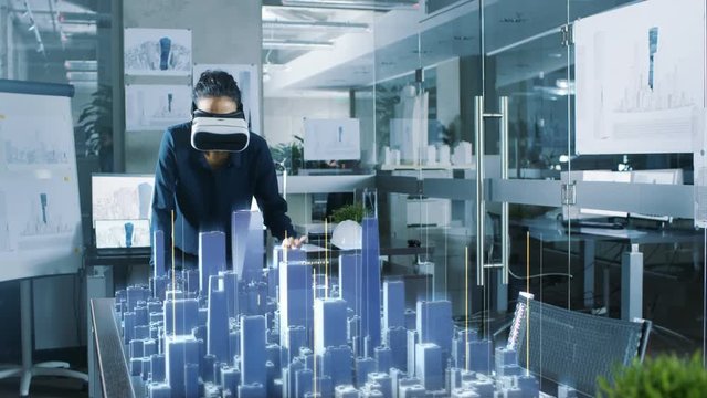 Professional Female Architect Wearing Makes Gestures with Augmented Reality Headset, Shows Statistics for 3D City Model. High Tech Office Use Virtual Reality Modeling Software Application.