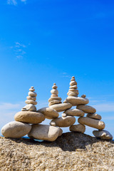 Fototapeta na wymiar High pyramid of white stones balance on the edge of the cliff on the sea background. Concept of harmony and balance