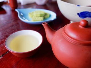 Traditional chinese tea set compose of cup of tea, teapot, and snack on wooden background
