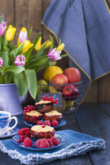 Home-made pastries with red currants and raspberries. Cupcakes for breakfast. A bouquet of spring flowers. Tulips yellow and red. Card.