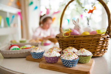 Easter celebration, close-up table with glazed cupcakes, basket with Easter eggs and bunny. Happy...