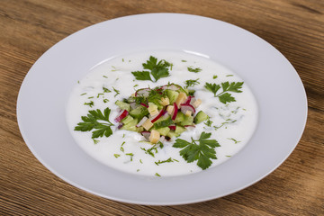 Okroshka. Summer light cold vegetable soup with cucumber, radish, eggs and dill on a wooden table. A traditional dish of russian or ukrainian cuisine.