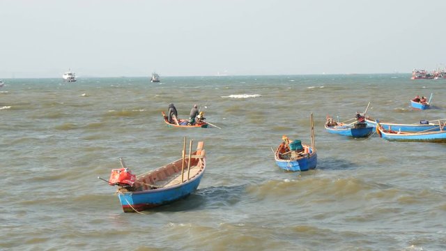 PATTAYA, THAILAND - DECEMBER 25, 2017: Small fishing boats sail along the lush sea on the waves. Fishermen catch fish in sea