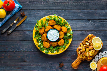 Chicken nuggets with yogurt sauce on a wooden background